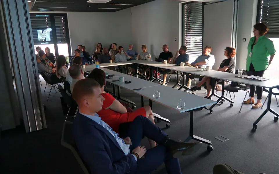Uczestnicy spotkania IZBy rozmawiają przy stołach w sali konferencyjnej